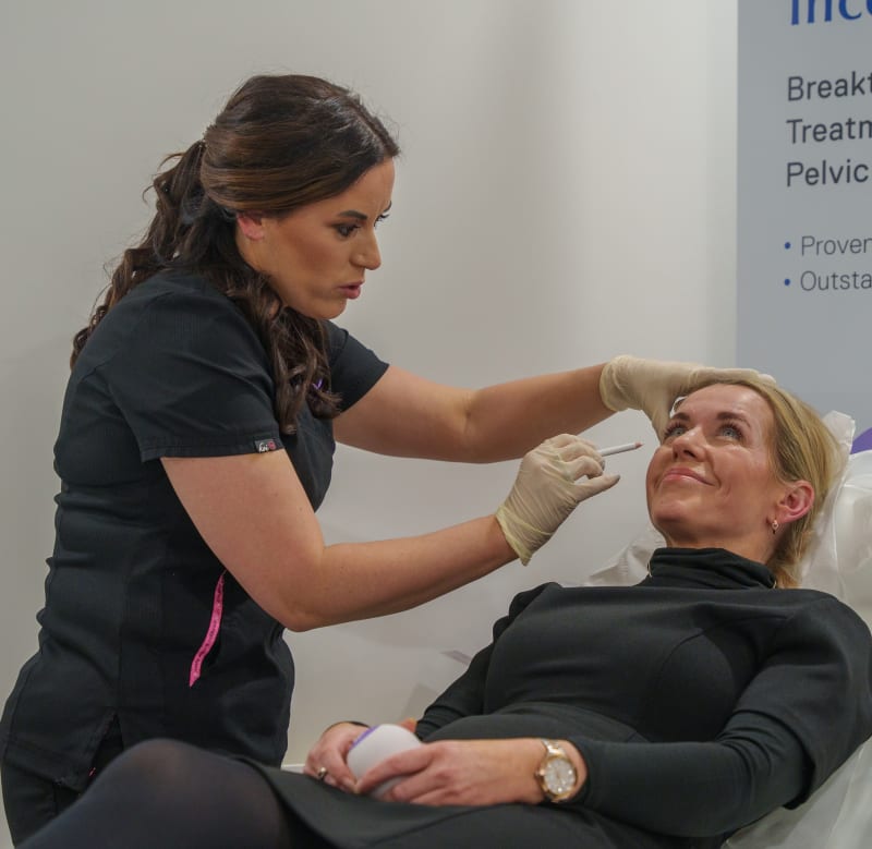 Aesthetic practitioner administering an injectable facial treatment to a smiling woman at Thérapie Clinic.
