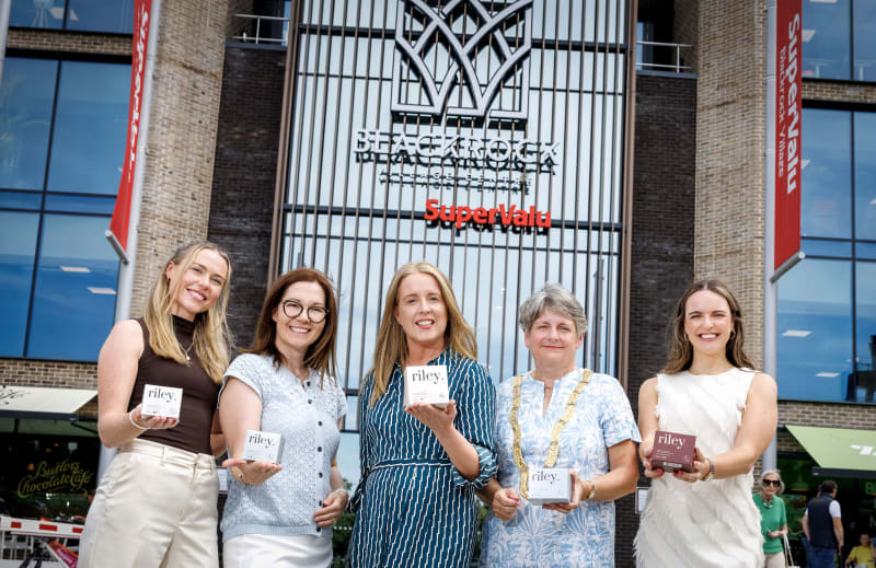 Five women holding riley. branded product boxes outside Blackrock Village Centre SuperValu.