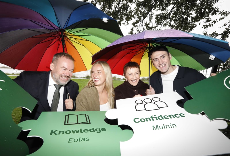 Four people holding rainbow umbrellas and puzzle pieces labelled Knowledge and Confidence at Mindshift Ireland launch.