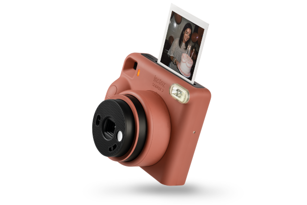Fujifilm Instax Square SQ1 instant camera in terracotta orange with a square photo ejecting from the top.